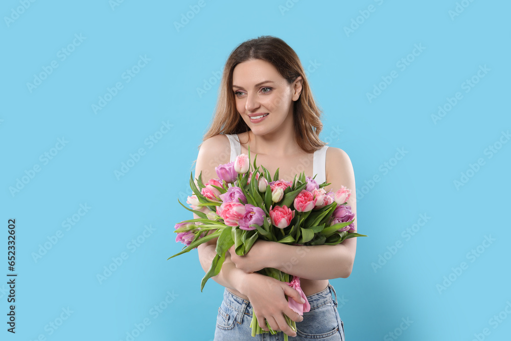 Happy young woman with bouquet of beautiful tulips on light blue background Happy young woman with bouquet of beautiful tulips on light blue background