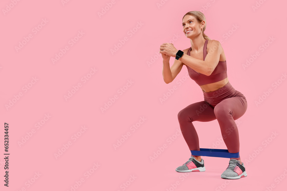 Woman exercising with elastic resistance band on pink background, low angle view. Space for text Woman exercising with elastic resistance band on pink background, low angle view. Space for text