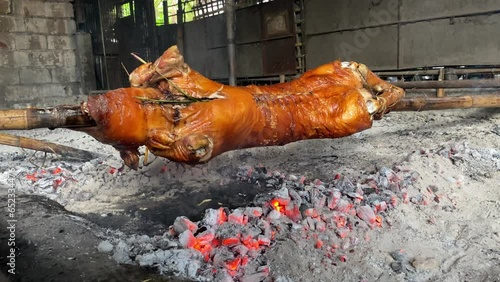 Making lechon in the traditional way. A whole pig on a spit over the coals photo