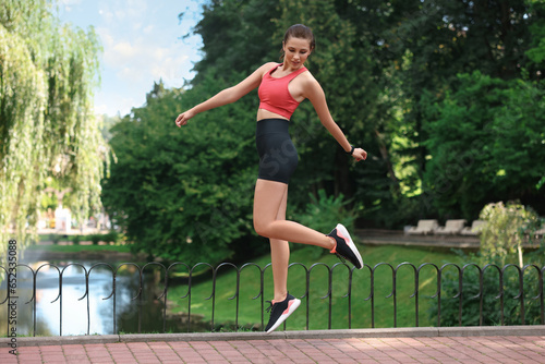 Beautiful woman in sportswear jumping in park