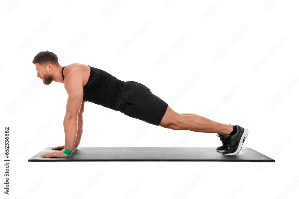 Young man exercising with elastic resistance band on fitness mat against white background Young man exercising with elastic resistance band on fitness mat against white background