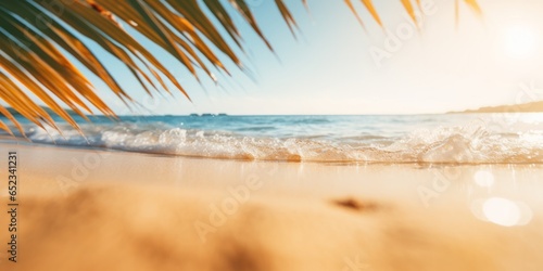 Golden sand of a tropical beach, blurred palm leaves and sea on a sunny day. Beautiful background for summer holidays and travel