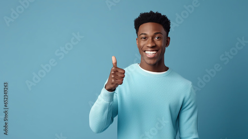 young man on blue background smiling with thumb up