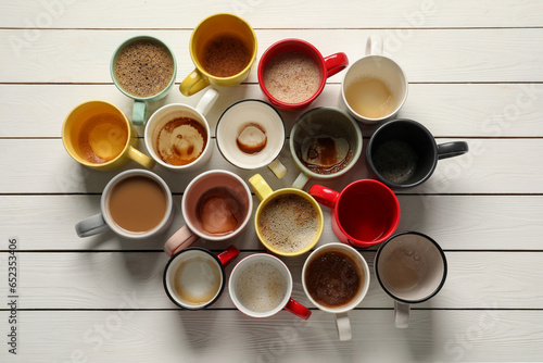 Many different cups with aromatic coffee and dirty ones on white wooden table, flat lay