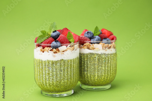 Tasty matcha chia pudding with oatmeal and berries on green background. Healthy breakfast