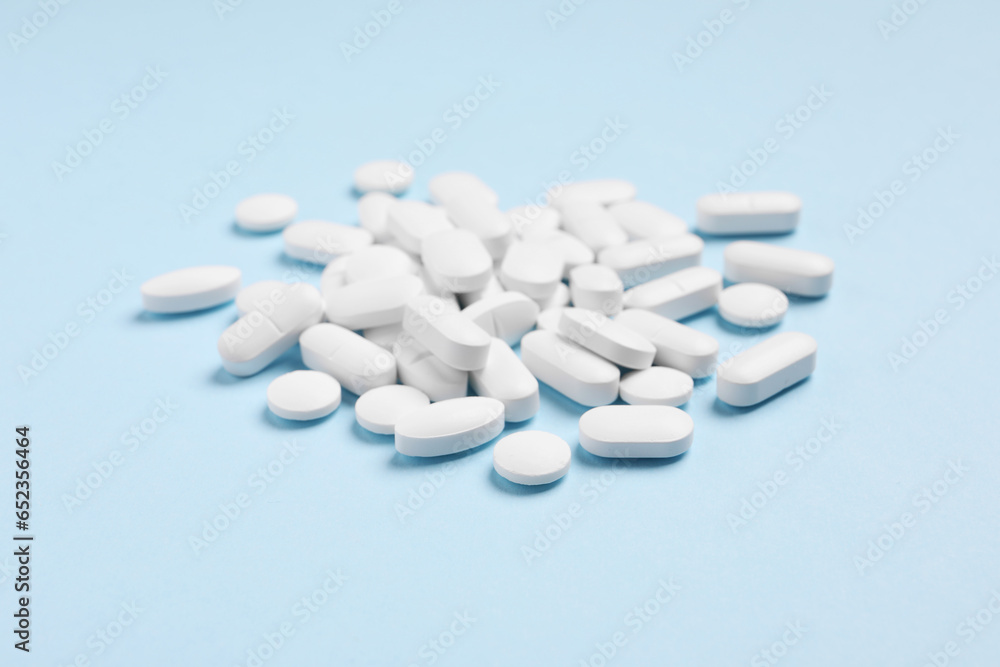 Pile of pills on light blue background
