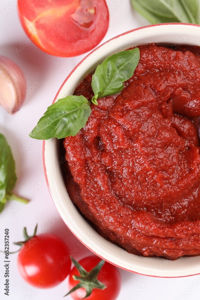 Tasty tomato paste in bowl and ingredients on white table, flat lay Tasty tomato paste in bowl and ingredients on white table, flat lay