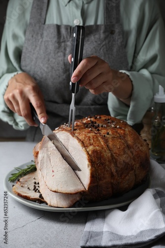 Woman cutting delicious baked ham at wooden table, closeup