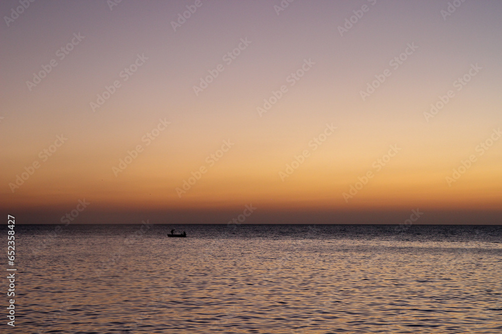 sunset on the beach with a fishing boat