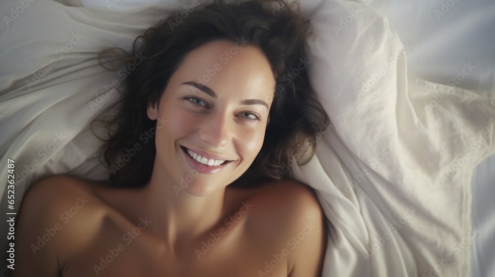 Beautiful brunette long hair woman lies on white bed linen in soft morning light. top view Beautiful brunette long hair woman lies on white bed linen in soft morning light. top view