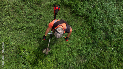 High angle view of modern gardener mows the grass with lawn mower. photo