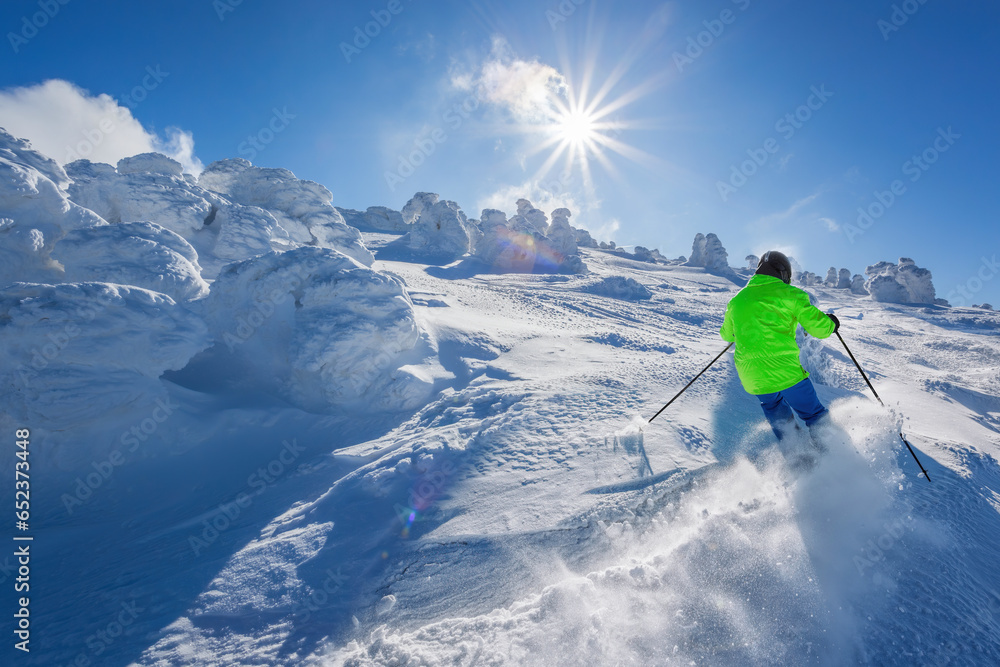 Skier skiing downhill in high mountains against the fairytale winter forest.