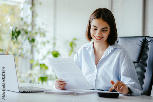 Accountant woman doing work at her desk with paper and calculator.