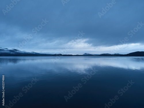 View of a lake in a winter blue hour in the evening. The water makes a mirror effect to the sky