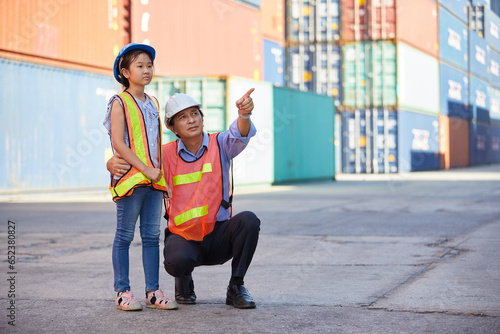 engineer or factory worker with her niece looking forward and pointing up to something in containers warehouse storage