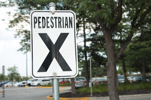 Foto pedestrian x vertical rectangle white black sign on metal post with parking lot