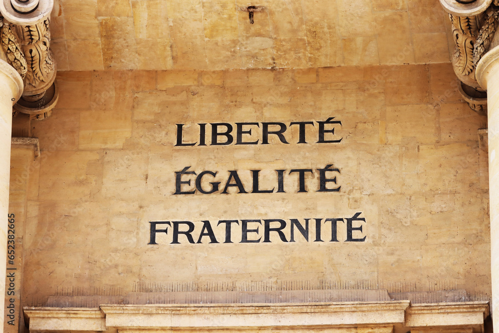 The famous French motto "Liberté, Égalité, Fraternité" in English "liberty, equality, fraternity" on the facade of the University of Paris, Faculty of Law. Paris, France - obrazy, fototapety, plakaty 