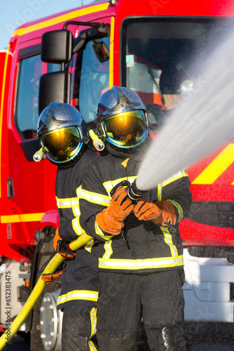 Pompiers devant un camion s'exerçant à lutter contre un incendie © Fanchy