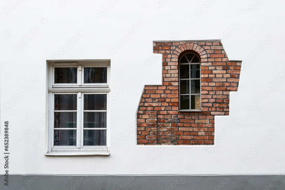 Obraz premium Textured natural stone wall background. light stone wall with windows with brick decor, facade of a residential building.
