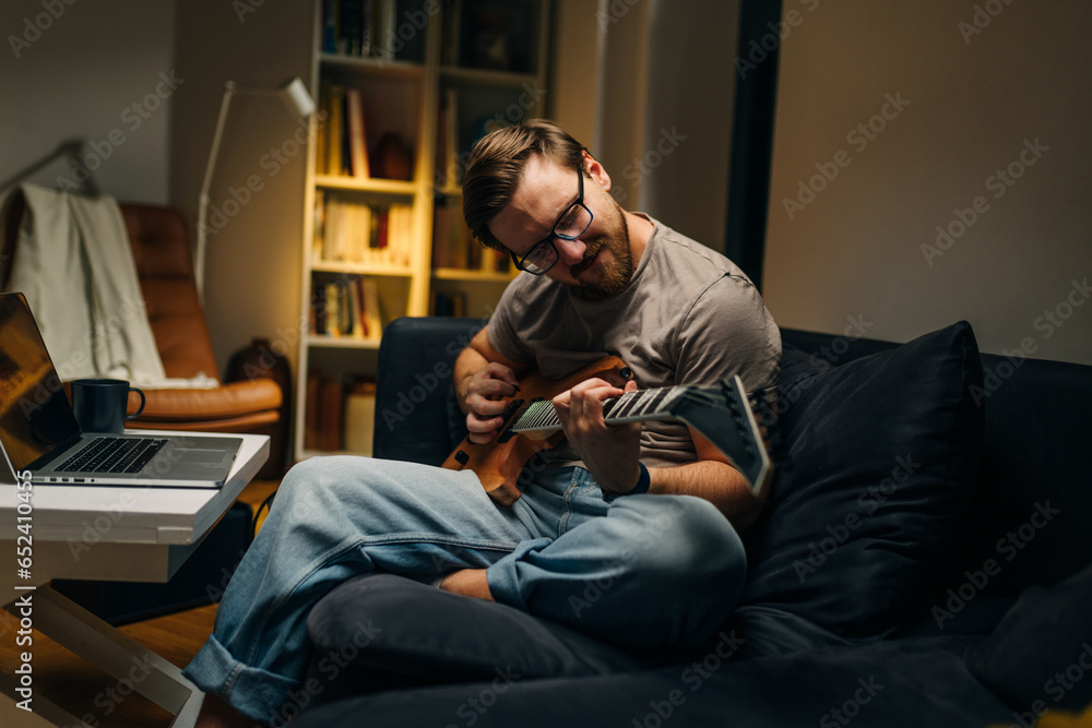 Caucasian man enjoys playing electric guitar.