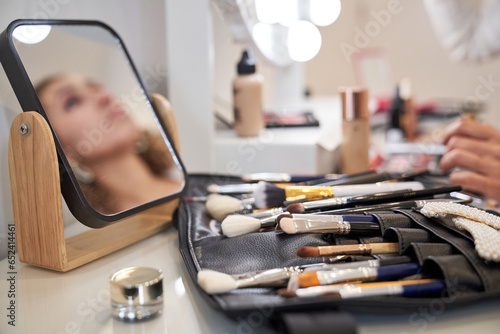 Fototapeta samoprzylepna Set of makeup professional brushes and mirror placed on table