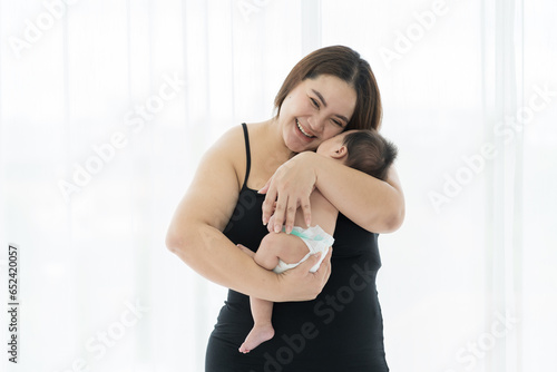 Asian young mother embrancing and carrying her newborn baby on white background. Happy Asian newborn baby and Asian young mother. family, love, happy and new life concept photo