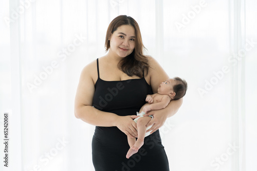 Asian young mother embrancing and carrying her newborn baby on white background. Happy Asian newborn baby and Asian young mother. family, love, happy and new life concept photo