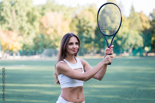 Sporty woman with a rocket on tennis court, beautiful female tennis player in training © staras