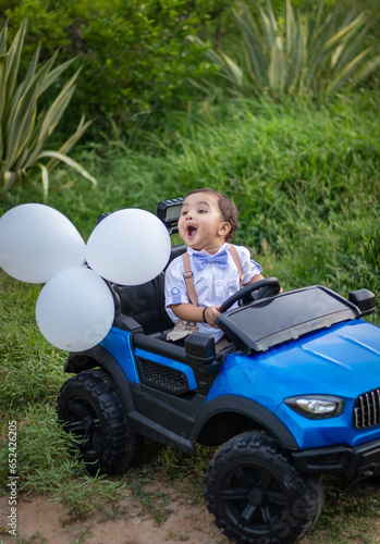 isolated cute toddler with innocent facial expression at toy car at outdoor from different angle
