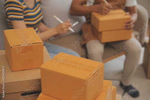 Startup small business owner working with computer at workplace. Freelance two woman seller check product order. Packing goods for delivery to customer. Online selling. E-commerce. Online Shopping
