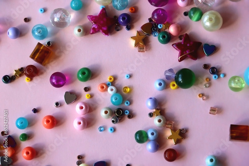 Various colorful beads on bright pink background. Top view.