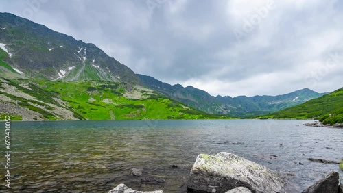 Famous mountains lake Five Polish Ponds Valley in Tatra national park, Poland, Zakopane region. Dramatic cloudscape over the green mountains peaks and Front pond (Przedni Staw) photo