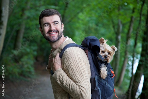 Man hiking with cute dog inside his backpack 