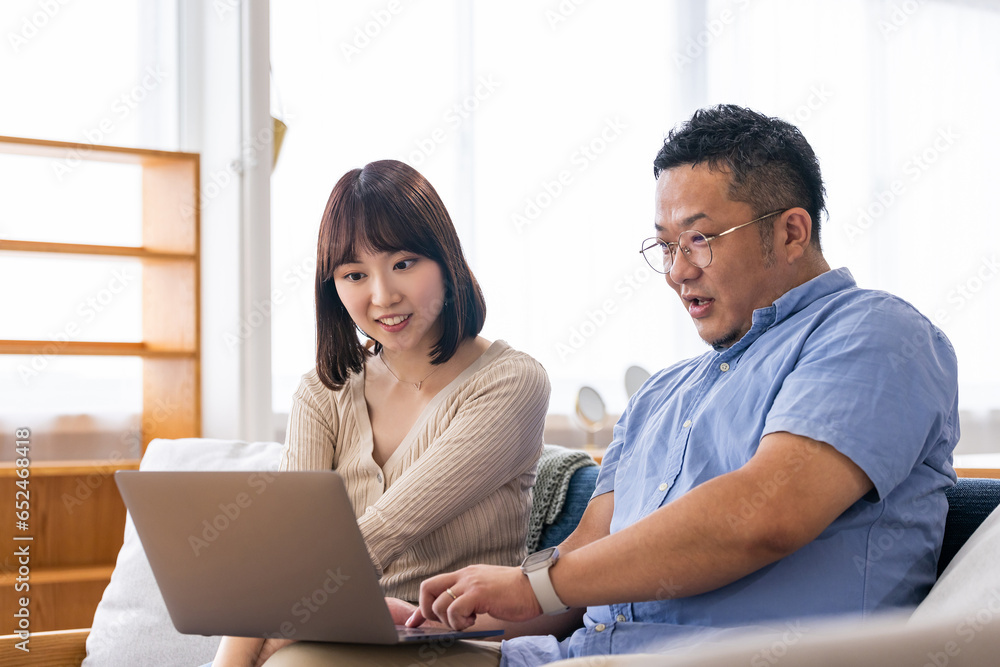 リビングでノートパソコンを使う男女 リビングでノートパソコンを使う男女