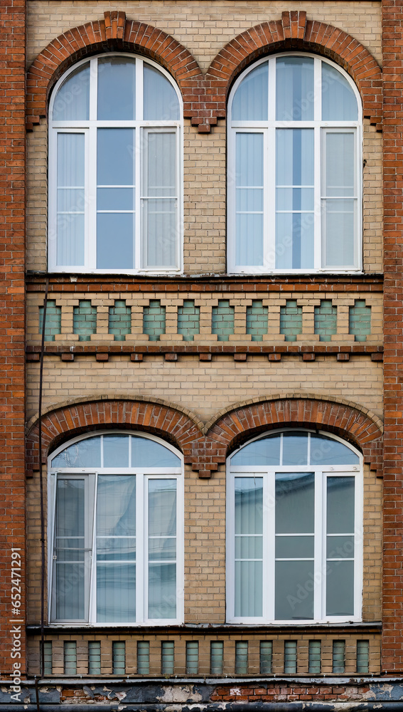 Red brick wall of apartment building with vaulted windows