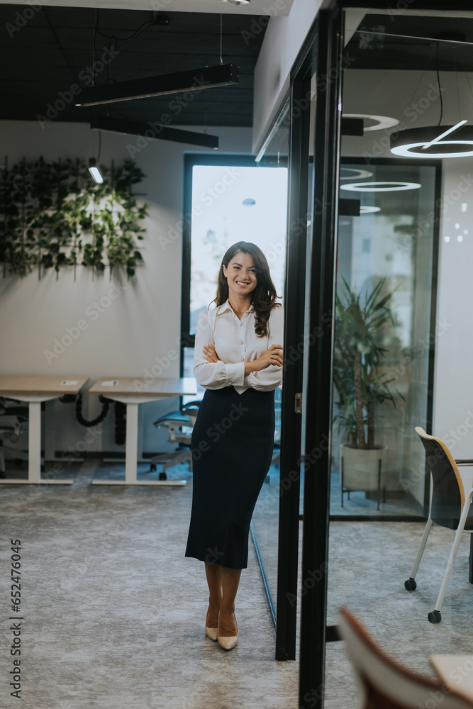 Young business woman standing with arms crossed in the modern office
