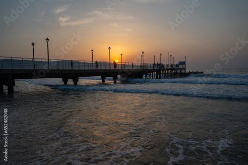 Pier in the sea with sun rising from the sea.