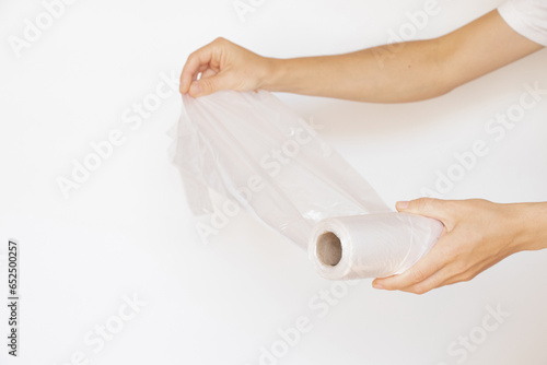 Female hands hold a roll of disposable plastic bags on a white background, disposable bags, plastic bag, ecology photo