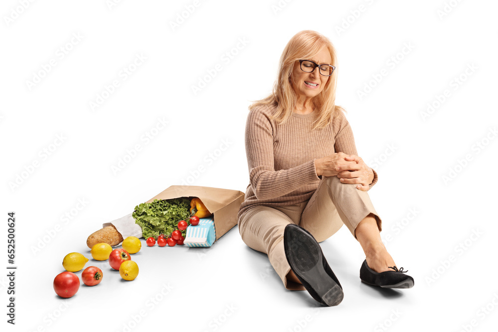 Fotografie Woman with a grocery bag and injured knee sitting on ground