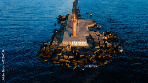 An orange lighthouse at the end of the Mangalsala or Eastern pier in Riga, Latvia where the river Daugava flows into the Baltic Sea.