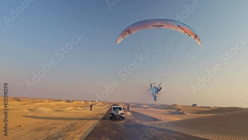 Epic shot of motorcyclists, car and paramotor speeding down the same desert road photo