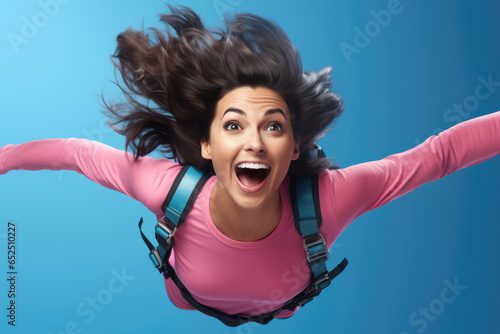 A woman wearing a pink shirt is captured in mid-air, defying gravity. This dynamic image can be used to depict freedom, adventure, or a sense of liberation.