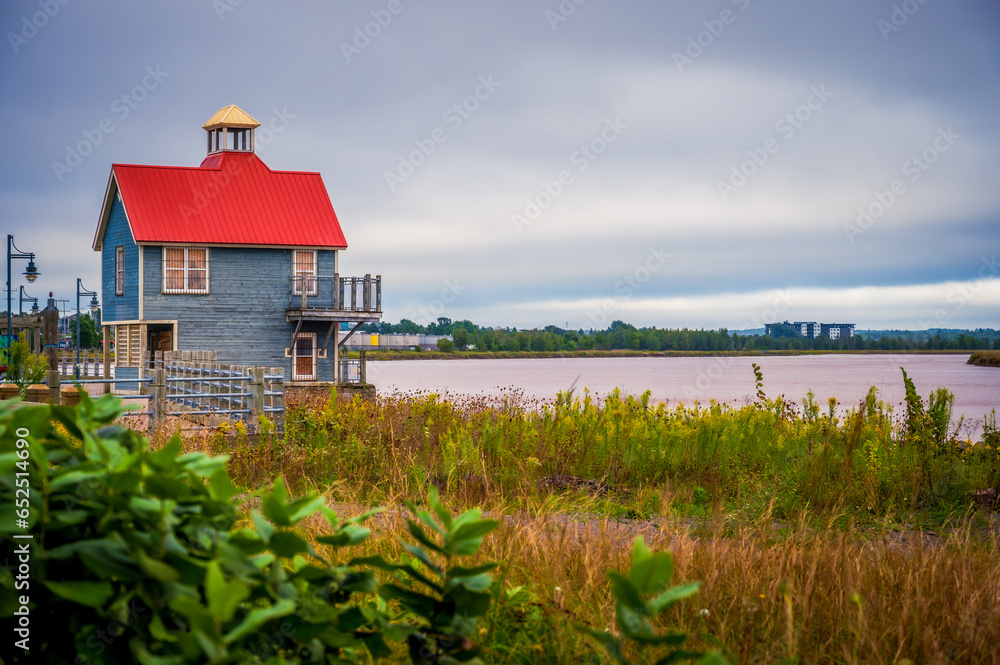 Petitcodiac River and small building with red roof with dramatic sky
