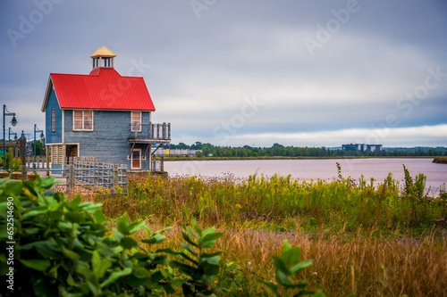 Petitcodiac River and small building with red roof with dramatic sky, Bore Park, Moncton, New Brunswick, Canada. Photo taken in September 2023.