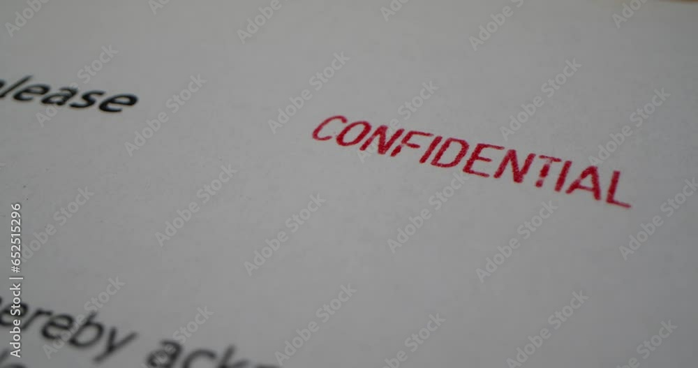 A stamp CONFIDENTIAL is placed on a sheet of white paper, close-up A stamp CONFIDENTIAL is placed on a sheet of white paper, close-up