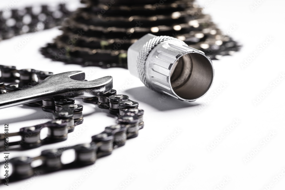 bicycle sprocket and chain lying on white background, next to bicycle repair tools (selective focus)