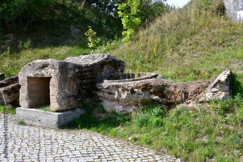 A close up on the remnants of an old concrete bunker or bomb shelter standing on the top of a tall hill next to some road and pavement seen on a sunny summer day on a Polish countryside