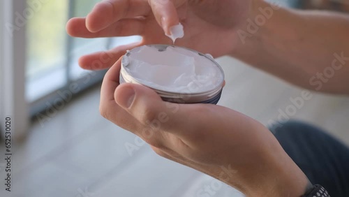 A man holds a restorative cream or balm in his hands, closeup. Men's skincare line photo