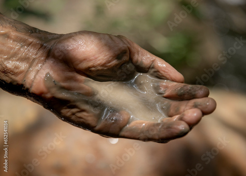 Detail of man holding wet clay at a natural spring spa