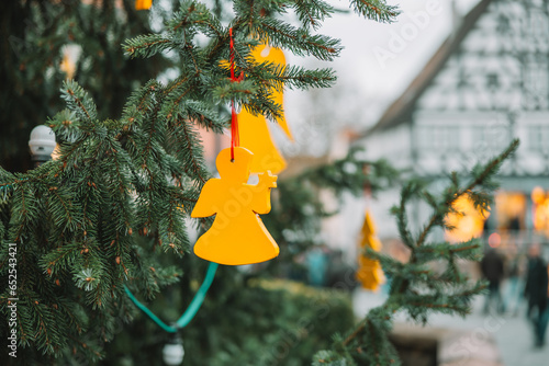  Christmas angel on a fir branch on an old city background.Christmas street decorations in European cities.Wooden Outdoor Decor for Trees.